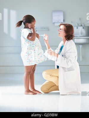Girl listening to doctors stethoscope in hospital children's ward Stock Photo