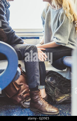 Neck down view of romantic young couple travelling in train carriage, Italy Stock Photo