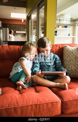 Siblings using digital tablet on sofa Stock Photo