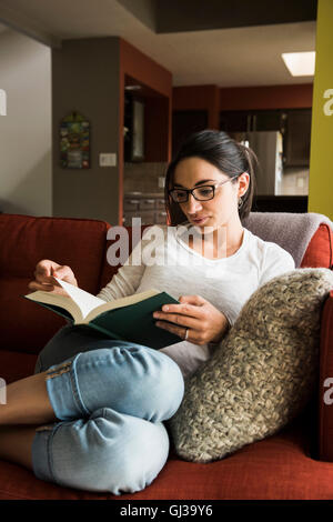 Woman reading book on sofa Stock Photo