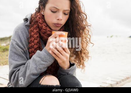 Young woman blowing into cup of coffee on cold day Stock Photo