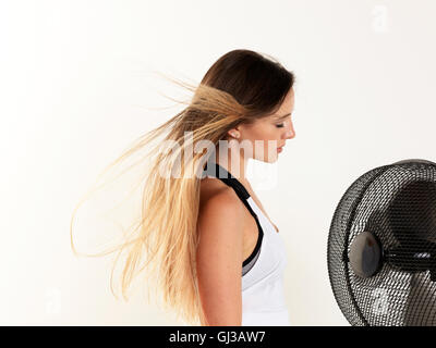 Woman cooling down in front of fan, white background Stock Photo