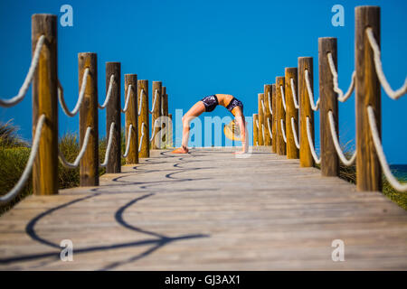 Young woman on wooden pathway, exercising, bent over backwards Stock Photo