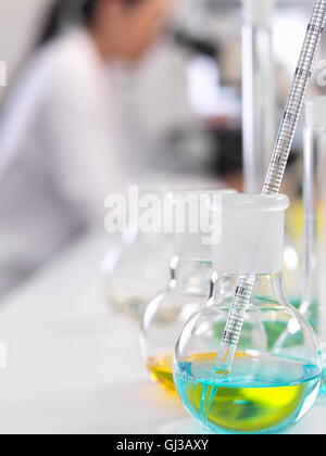 A scientist looking down a microscope with a chemical formula in the foreground Stock Photo