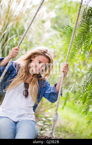Happy young woman swinging on garden swing Stock Photo