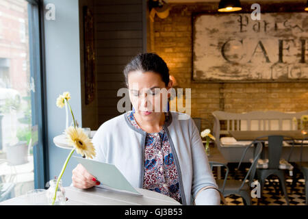 Mature female customer reading menu in cafe Stock Photo