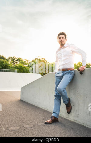 Smart young man leaning against wall Stock Photo