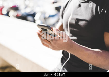 Young man outdoors, holding smartphone, mid section Stock Photo