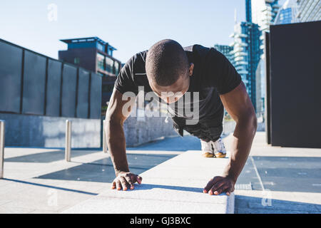 Young man exercising outdoors, doing push-ups Stock Photo
