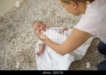 Swaddling Step 2. Mother preparing baby boy lying on blanket Stock Photo