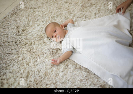 Swaddling Step 3. Mothers hands covering baby boy with blanket Stock Photo