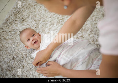 Over shoulder view of mother swaddling baby boy with blanket Stock Photo