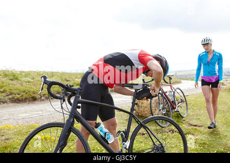 Cyclists fixing saddle on roadside Stock Photo