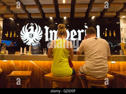 A young couple sitting at a bar having a drink, rear view, San Jose airport ,Costa Rica Stock Photo