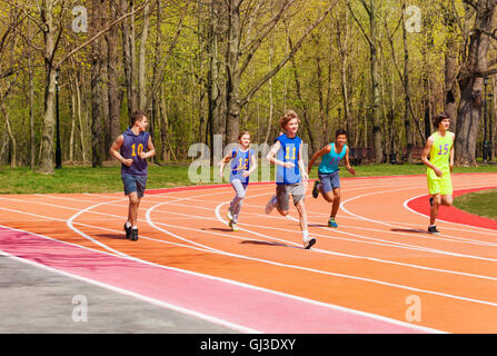 Five running teenage athletes in the stadium Stock Photo
