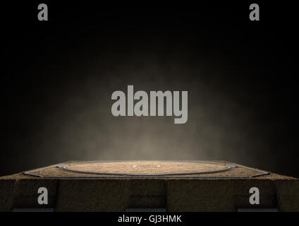 A 3D render of an empty traditional sumo wrestling ring made with sand dimly lit by spotlights on a dark background Stock Photo