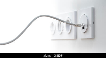 Close-up of an ethernet cable plugged into a wall socket, horizontal image with free space for text Stock Photo