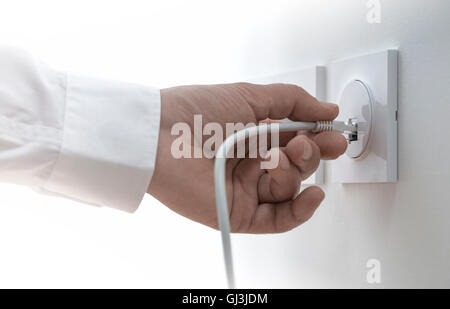 Close-up of a man hand plugging an ethernet cable into a wall socket, horizontal image. Concept of broadband network Stock Photo