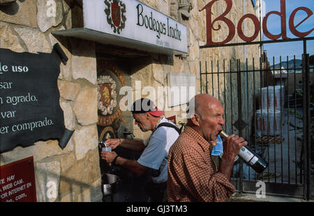 Pilgrims drinking red wine here at the back of 'Bodegas Irache' a winery that since 1991 has spouted free red wine for the benefit of travellers on the road! This Fuente del Vino (the Wine Fountain) had a note mentioning that the wine was not meant for children or to be bottled for selling. In Navarra province. Stock Photo