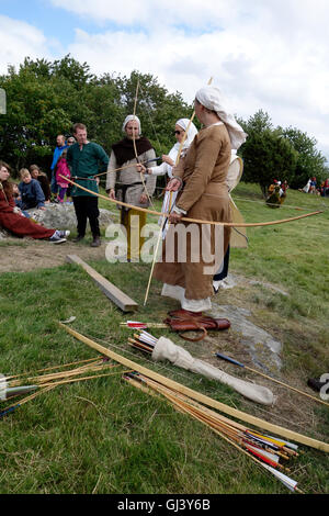 Medieval re enactment. Middle aged woman shoots a longbow. Stock Photo