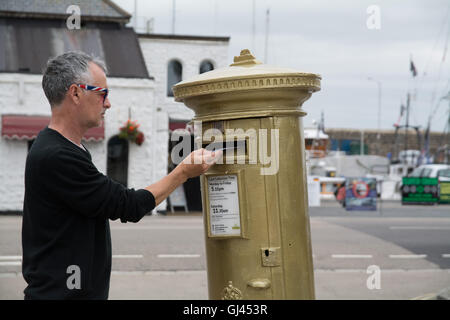 Penzance, Cornwall, UK. 12th August 2016.  The golden postbox in Penzance in honour of Helen Glover winning gold in the 2012 Olympics. Helen is due to race in the Coxless pairs with Heather Stanning at Rio, and are going for gold again ! Credit:  Simon Maycock/Alamy Live News Stock Photo