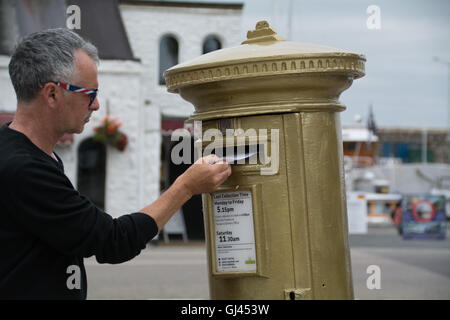 Penzance, Cornwall, UK. 12th August 2016.  The golden postbox in Penzance in honour of Helen Glover winning gold in the 2012 Olympics. Helen is due to race in the Coxless pairs with Heather Stanning at Rio, and are going for gold again ! Credit:  Simon Maycock/Alamy Live News Stock Photo