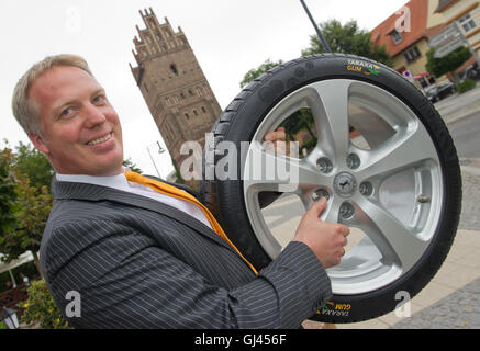 Anklam, Germany. 12th Aug, 2016. Alexander Bahlmann worker from Continental Reifen Deutschland GmbH shows a car tire of the auto supplier Continental bears the lettering 'Taraxa Gum' in Anklam, Germany, 12 August 2016. At the press conference in Anklam the car tire of the auto supplier Continental bears the lettering 'Taraxa Gum'. The tread of the tire natural rubber is processed from dandelion. The tire manufacturer Continental built in the city of Greifswald a research and development site to attract natural rubber from dandelions. Photo: STEFAN SAUER/dpa/Alamy Live News Stock Photo