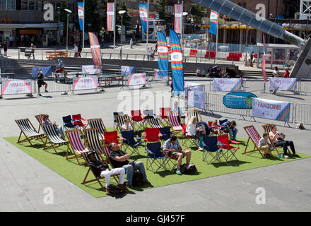 Coventry, UK. 12th August, 2016. UK Weather. People enjoy the warm sunny weather whilst watching the big screen in the Rio Olympics Fanzone in Millennium Place in Coventry city centre. Credit:  Colin Underhill/Alamy Live News Stock Photo