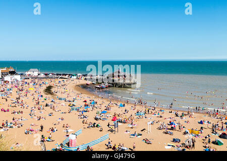 Broadstairs resort town in UK, the main beach with small harbour at one end. Hot summer day with lots of people and families on beach sunbathing. Stock Photo