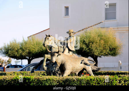 Statue of Guardian guiding a bull on the roundabout to the city center Camarguaise city of Saintes-Maries-de-la-Mer. Stock Photo