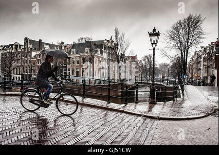A cyclist with an umbrella in the rain in Amsterdam Stock Photo