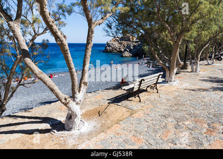 Single bench on Mavra Volia beach. Mavra Volia is a beach with small black volcanic pebbles near Emporios village in Chios Stock Photo