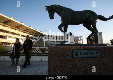 A couple at the statue of top horse 'Haiseiko' who won many of the best races in the early seventies and went on to sire many wi Stock Photo