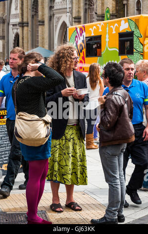 Flamboyant man chatting with friends on packed colourful street during the summer Brighton festival in Brighton, UK as of 2012 Stock Photo