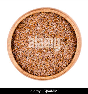 Brown flaxseeds in a wooden bowl on white background. Also known as common flax or linseed. Raw edible food. Linum usitatissimum Stock Photo