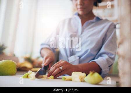 Cropped shot of female hands chopping fruits on the counter. Fruit juice bar employee preparing fresh juice. Stock Photo