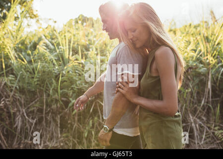 Side portrait of loving young couple walking in countryside. Beautiful young woman walking with her boyfriend outdoors on a sunn Stock Photo