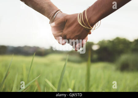 Close up shot of young couple holding hands in the field outdoors. Man and woman hand in hand on meadow. Stock Photo