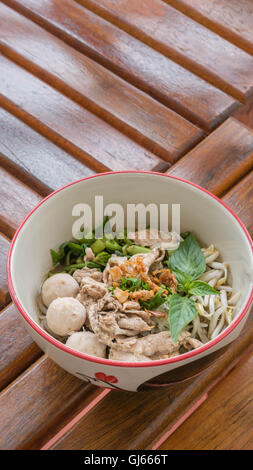 Asian white noodles with pork and vegetables in bowl over wooden background Stock Photo