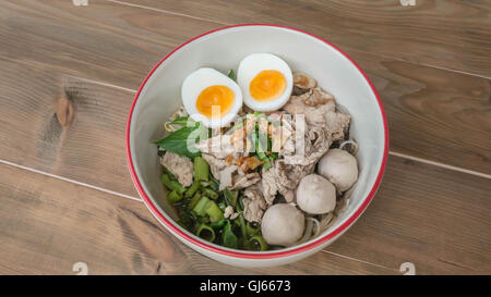 Asian white noodles with pork and vegetables in bowl over wooden background Stock Photo