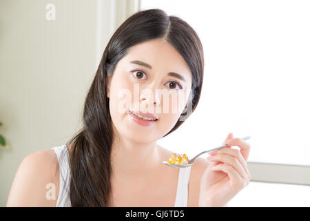 young beautiful asian woman eating nutritional supplement pill for healthy lifestyle at home Stock Photo