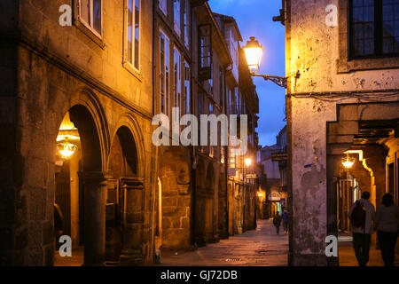 Thousands of visitors and pilgrims gather in Santiago de Compostela, especially on St James Day July 25th, but Santiago has many charms including the Old Town. Here the colonnaded street, Rua do Vilar, at twilight, one of the main streets within the Old Town. The cathedral is the famed goal of pilgrimages throughout Europe, the Camino de Santiago, to this spot in Galicia in the north west of Spain. Stock Photo