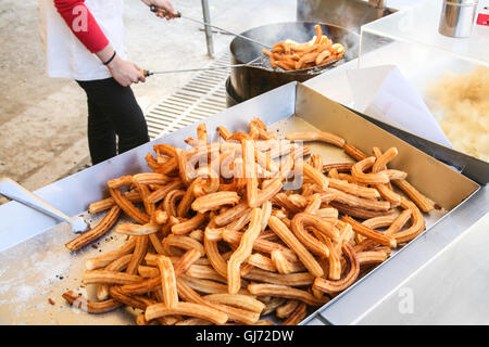 Frying churros, a very popular Spanish snack,typically crunchy outside and soft inside,this Spanish donought /donut often dipped Stock Photo