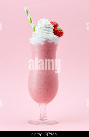 Glass of strawberry milkshake with whipped cream and fresh strawberries on pink background Stock Photo