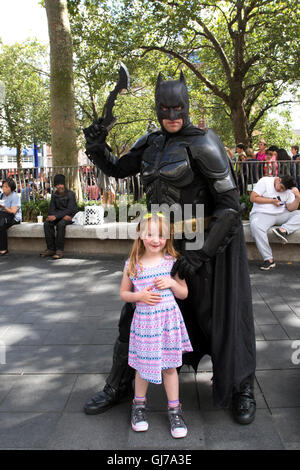 Young 6 year old girl posing for a photograph with Batman in Leicester Square in Central London Stock Photo