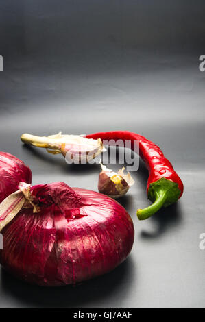 still life - sweet purple Crimean onion, garlic and Cayenne red pepper on black background Stock Photo