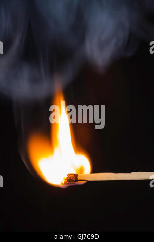 Match bursting into flame against a black background Stock Photo