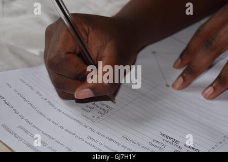 Black Girl Writing on a Piece of Paper Preparing for School Stock Photo