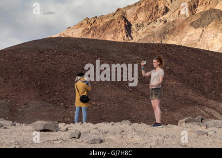 Woman taking selfies by the volcanic and sedimentary hills near Artist's Palette in Death Valley National Park, California, USA Stock Photo