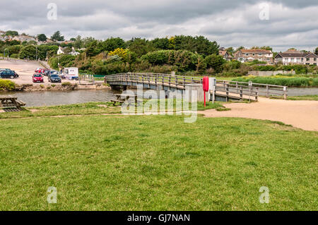 The river Char flows gently through picturesque countryside and under a wooden bridge before entering the sea h at Charmouth. Stock Photo